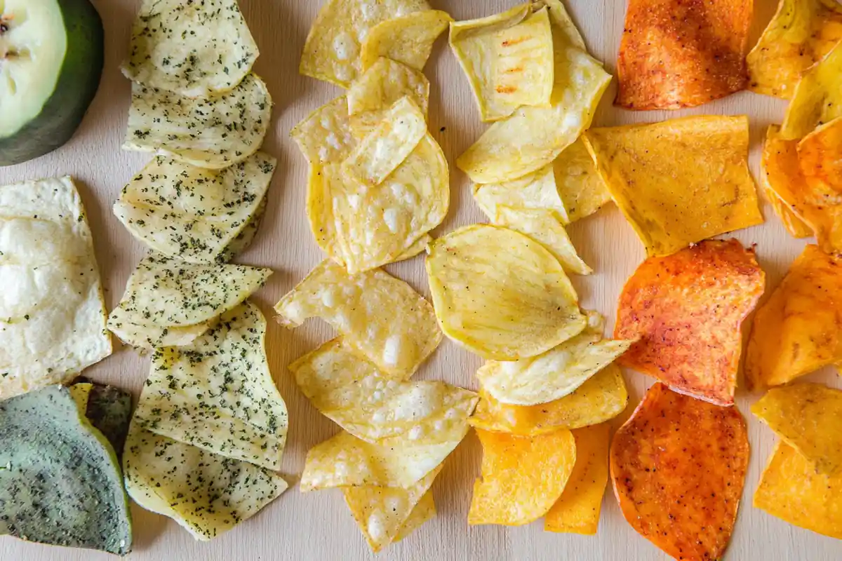 A colorful assortment of plantain chips, some baked, some seasoned, with fresh plantain slices